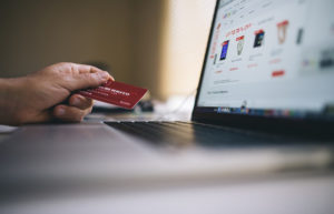 Comercio digital en la pantalla de un portátil cuyo usuario tiene una tarjeta de crédito en la mano