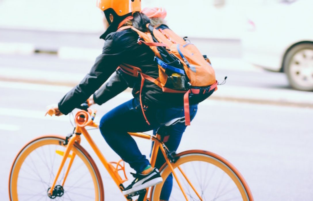 Ciclista con mochilla naranja y negra. Moverse en bicicleta es una forma de hacer salud.